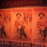 Werbeplakate der Buffalo Bill's Wild West Show, auf denen Buffalo Bill auf einem Stuhl sitzt