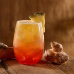 Orange-Roter Cocktail mit einem Stück Ananas am Glasrand