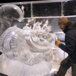 Ein Künstler arbeitet an einer Eisskulptur in Form der Grinsekatze