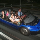 Ein blaues Auo mit Fahrgästen bei der Attraktion Test Track