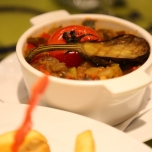 Ratatouille in einem Schälchen, garniert mit einer Cocktailtomate und einer halben Baby-Aubergine