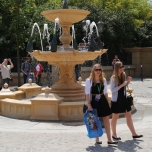 Springbrunnen am Place de Remy, davor zwei junge Frauen