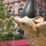 Eine Ratte als Wasserspeieer am Springbrunnen, aus ihrem Maul sprudelt das Wasser heraus