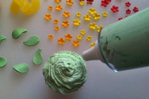 Grünes Frosting wird auf die Muffins aufgebracht