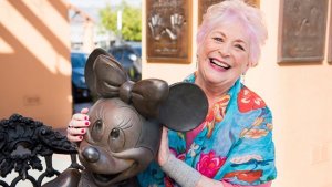 Russi Taylor, die Stimme von Minnie Mouse mit einer Statue von Ihr