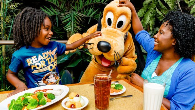 Pluto besucht eine Mutter und ihren Sohn an einem Tisch im Restaurant Garden Grill in Epcot