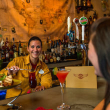 Eine Barkeeperin bereitet in Jock Lindsey's Hangar Bar einen Cocktail vor den Augen einer Besucherin zu