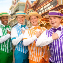 Die vier Dapper Dans stehen in ihren bunt gestreiften Anzügen auf der Main Street U.S.A. und posieren für ein Foto