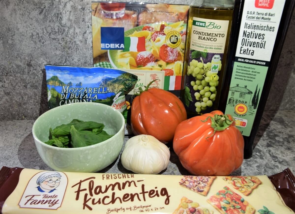 Auf einer Küchenarbeitsfläche liegen mehrere für das Oven Dried Tomato Flatbread benötigte Zutaten