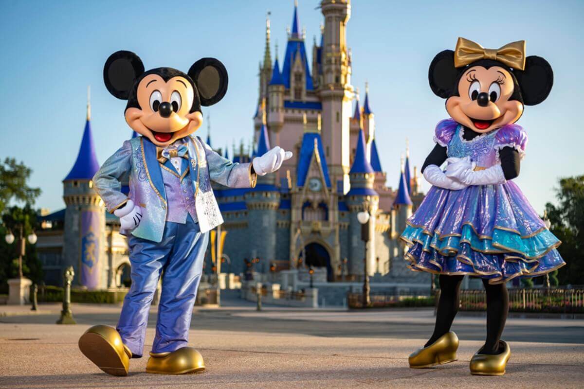 Mickey Mouse und Minnie Mouse in glitzernden Kleidern vor dem Cinderella Castle im Magic Kingdom