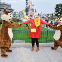 Eine junge Frau steht in einem Gaston-Disneybounding-Outfit zwischen Chip und Chap 