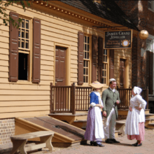 Drei Personen stehen im Freilichtmuseum Colonial Williamsburg vor einem Haus