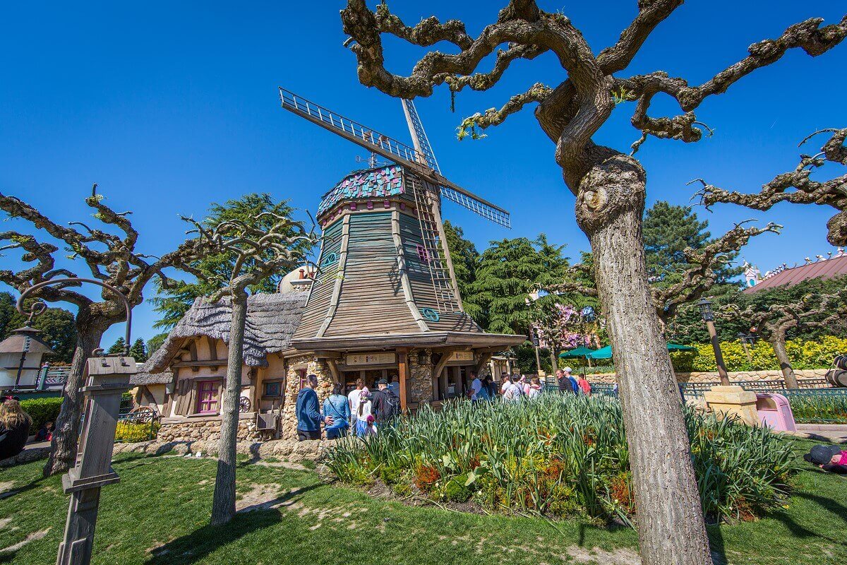 Inmitten einer grünen Fläche ist die alte Windmühle im Fantasyland des Disneyland Paris zu sehen