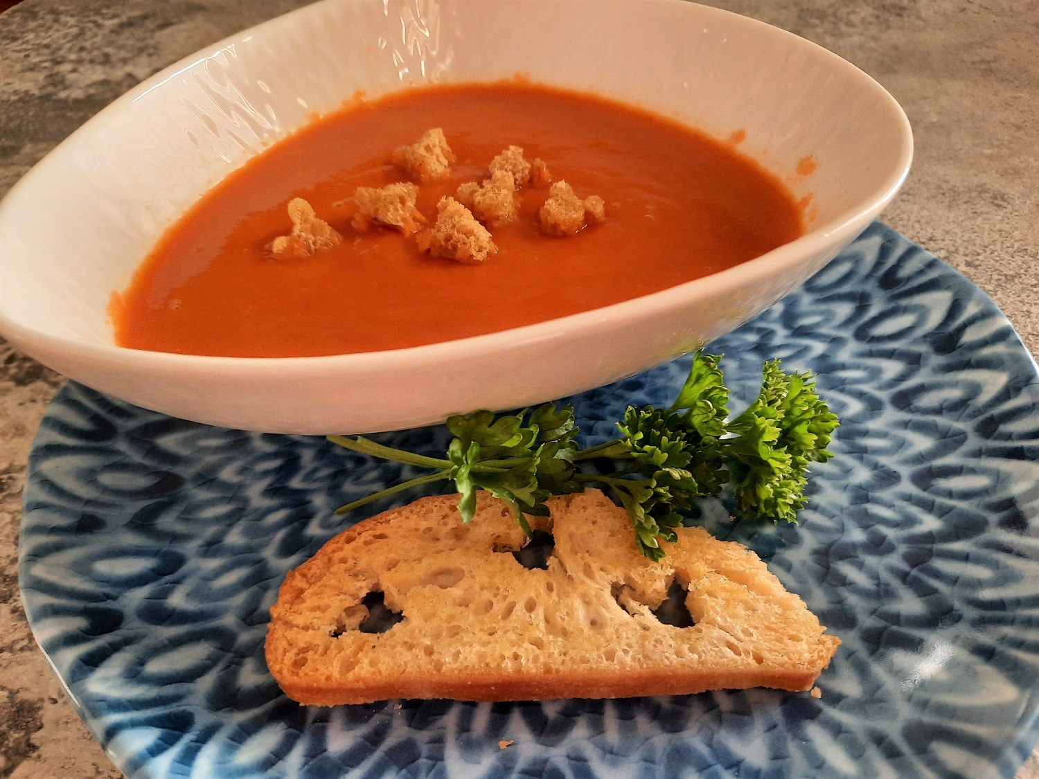 In einem Schälchen ist eine Portion selbstgemachte Tomatensuppe mit Croutons in Mickey Mouse-Form zu sehen