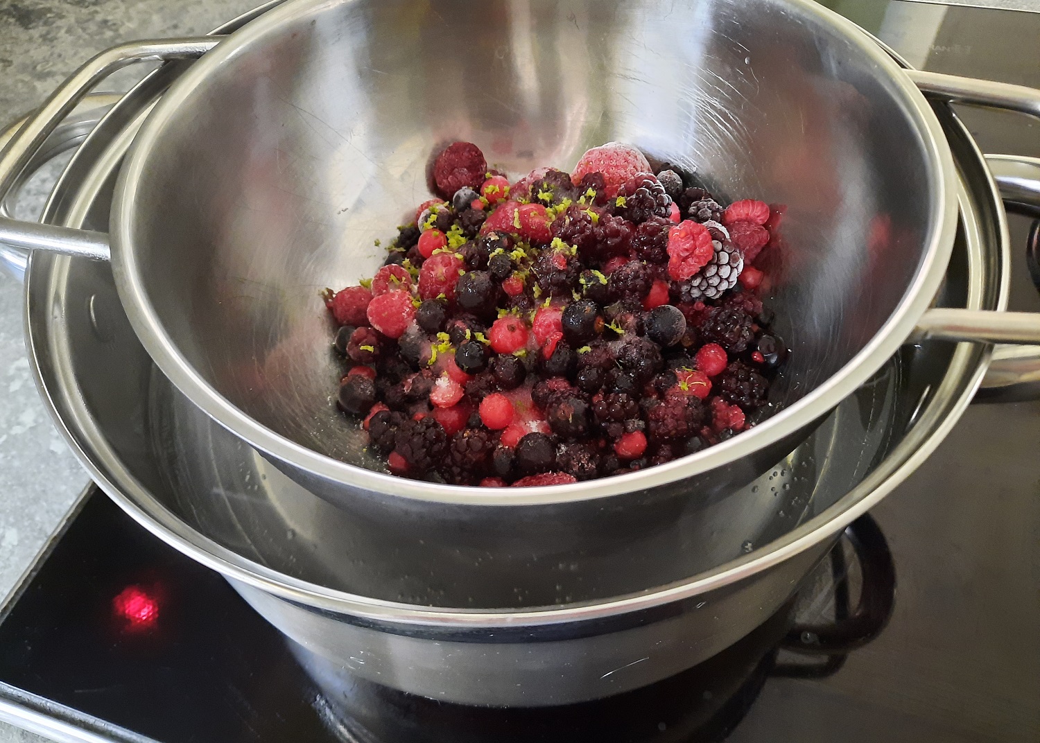 Tiefgefrorene Beeren werden in einem Topf über einem Wasserbad aufgetaut