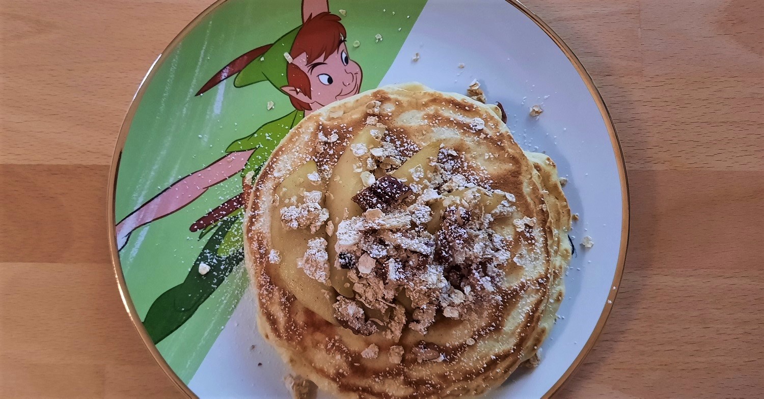 Pancakes mit Apfelspalten und Granola auf einem Teller mit Peter Pan-Motiv