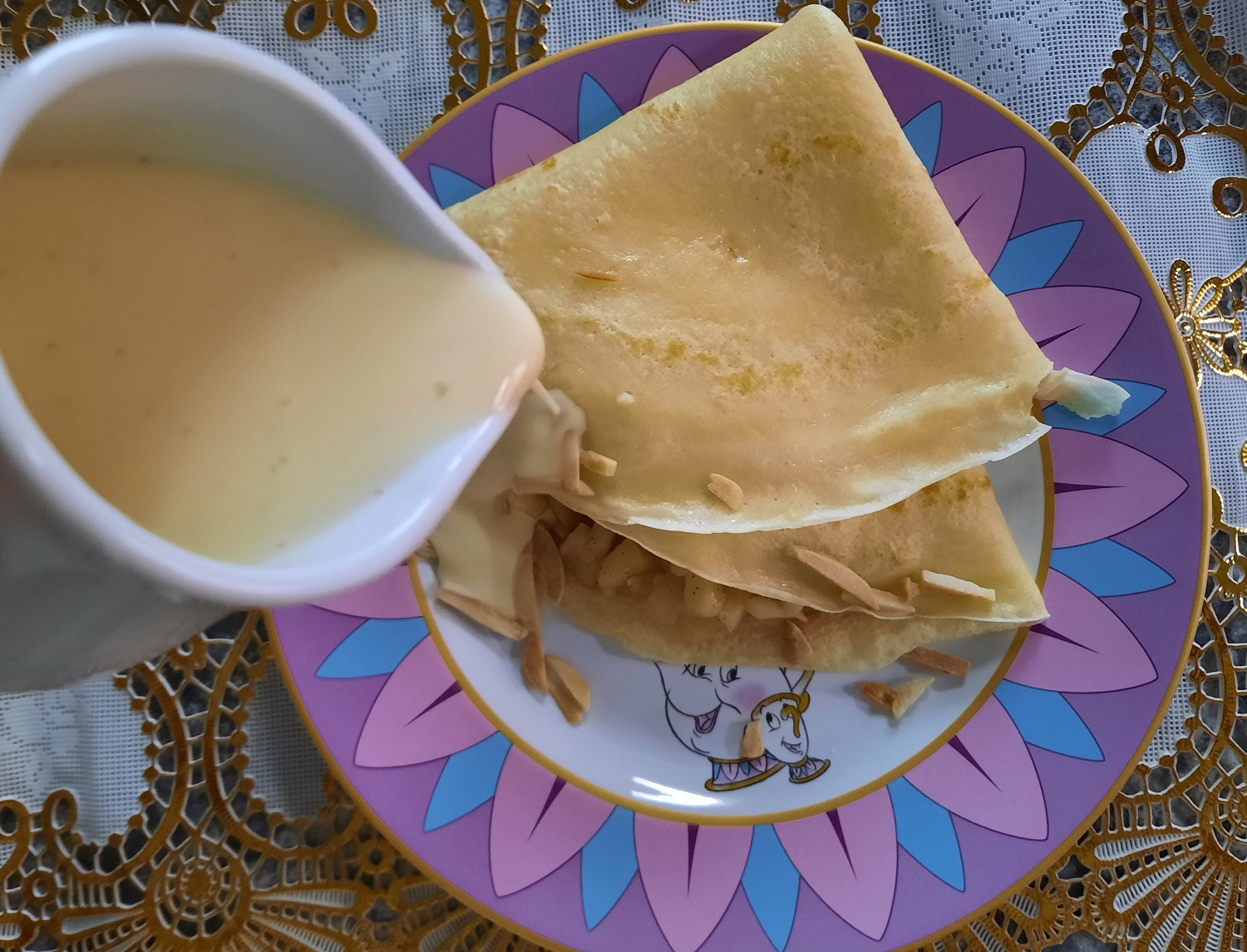 Ein Crepe mit Apfelfüllung wird mit Vanillesauce übergossen