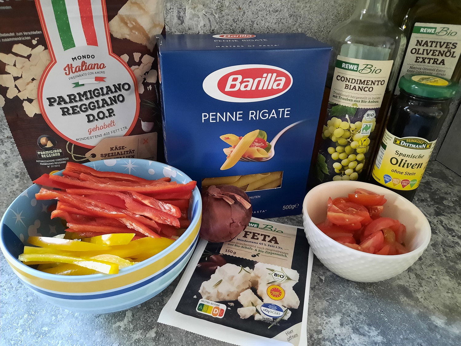 Verschiedene Zutaten für einen Nudelsalat mit Tomaten und Paprika