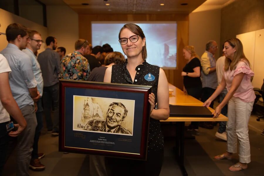 Leslie hält den Walt Disney Legacy Award mit einem Abbild von Walt Disney in der Hand