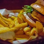 Burger mit Pommes Frites in einem mit Papier ausgelegten Korb