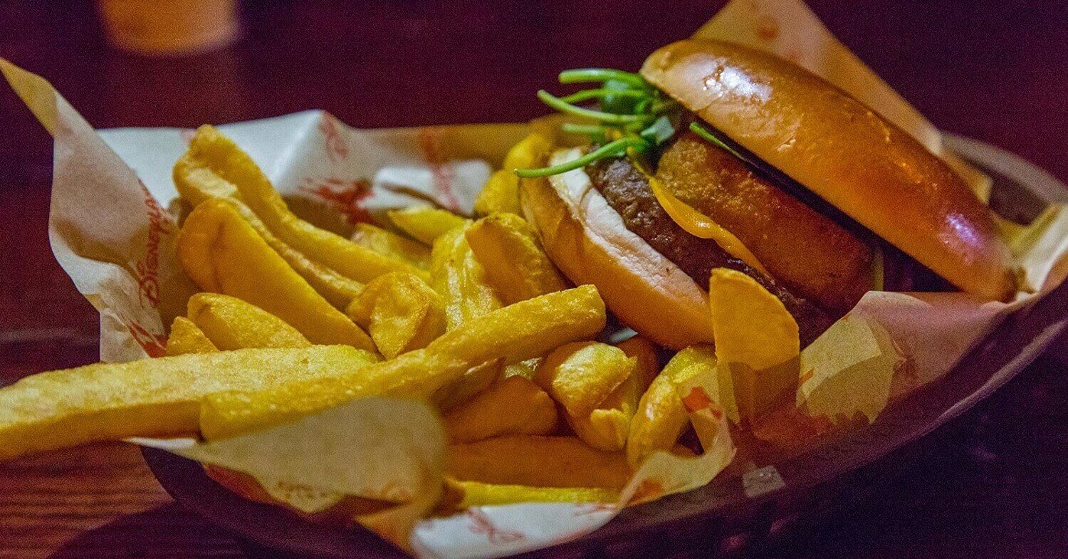 Burger mit Pommes Frites in einem mit Papier ausgelegten Korb