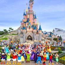 Gruppenfoto der Disney Figuren vor dem Sleeping Beauty Castle, rechts am Bildrand Natacha Rafalski