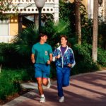 Zwei Personen in Sportkleidung joggen auf einem Pfad durch Disneys Caribbean Beach Resort