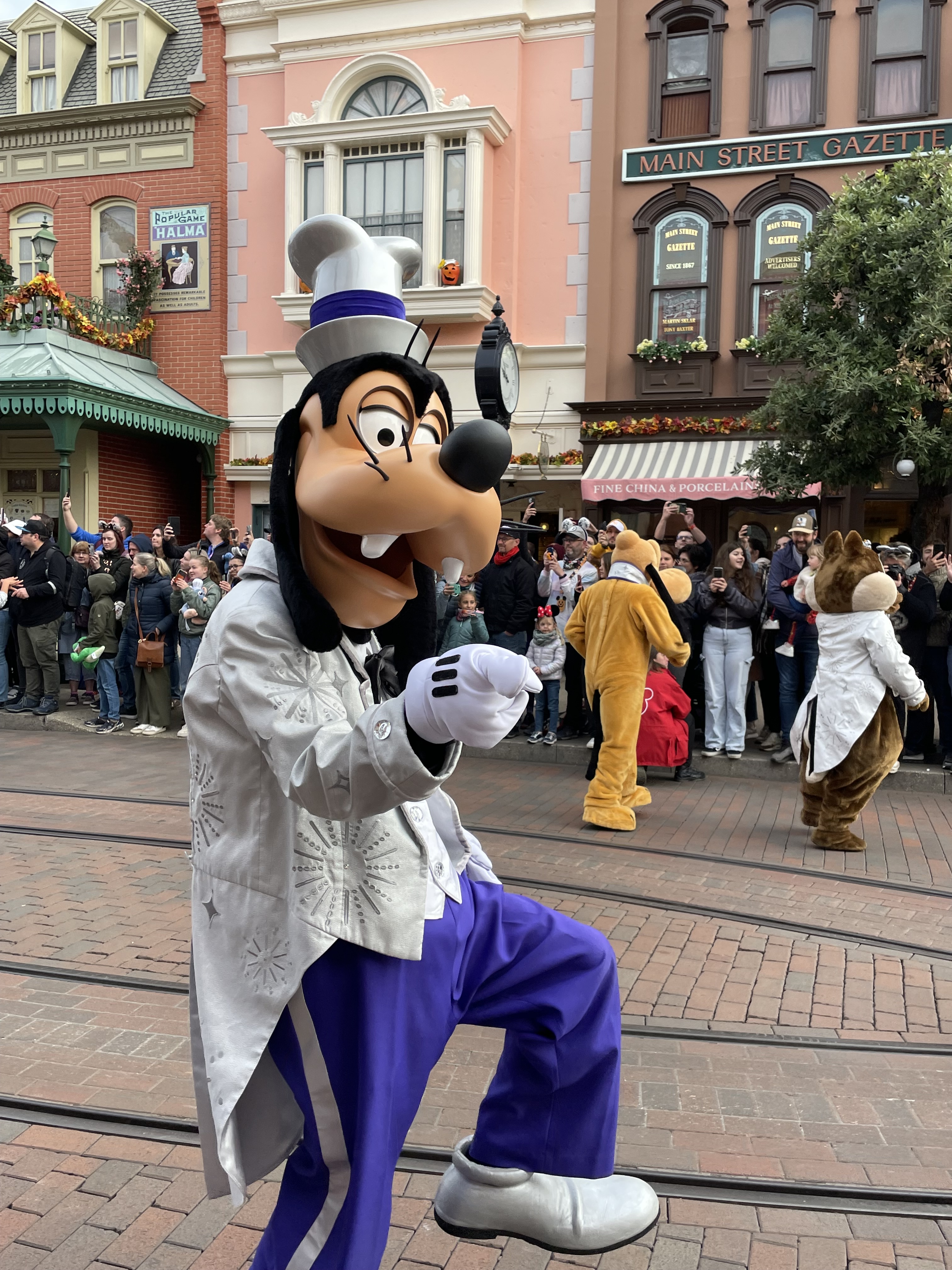 Goofy tanzt auf der Main Street USA im Disneyland Paris im weißen Frack und lilafarbener Hose.