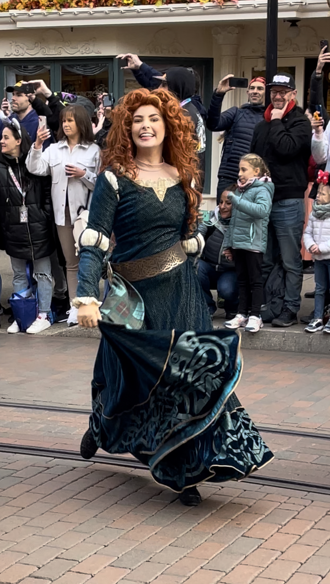 Merida schreitet bei der Disney 100 Parade über die Main Street, im Hintergund stehen Zuschauer am Straßenrand