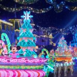 Mickys Dazzling Christmas Parade mit bunten Wagen und festlich gekleideten Charakteren bei Nacht in Disneyland Paris, 2023