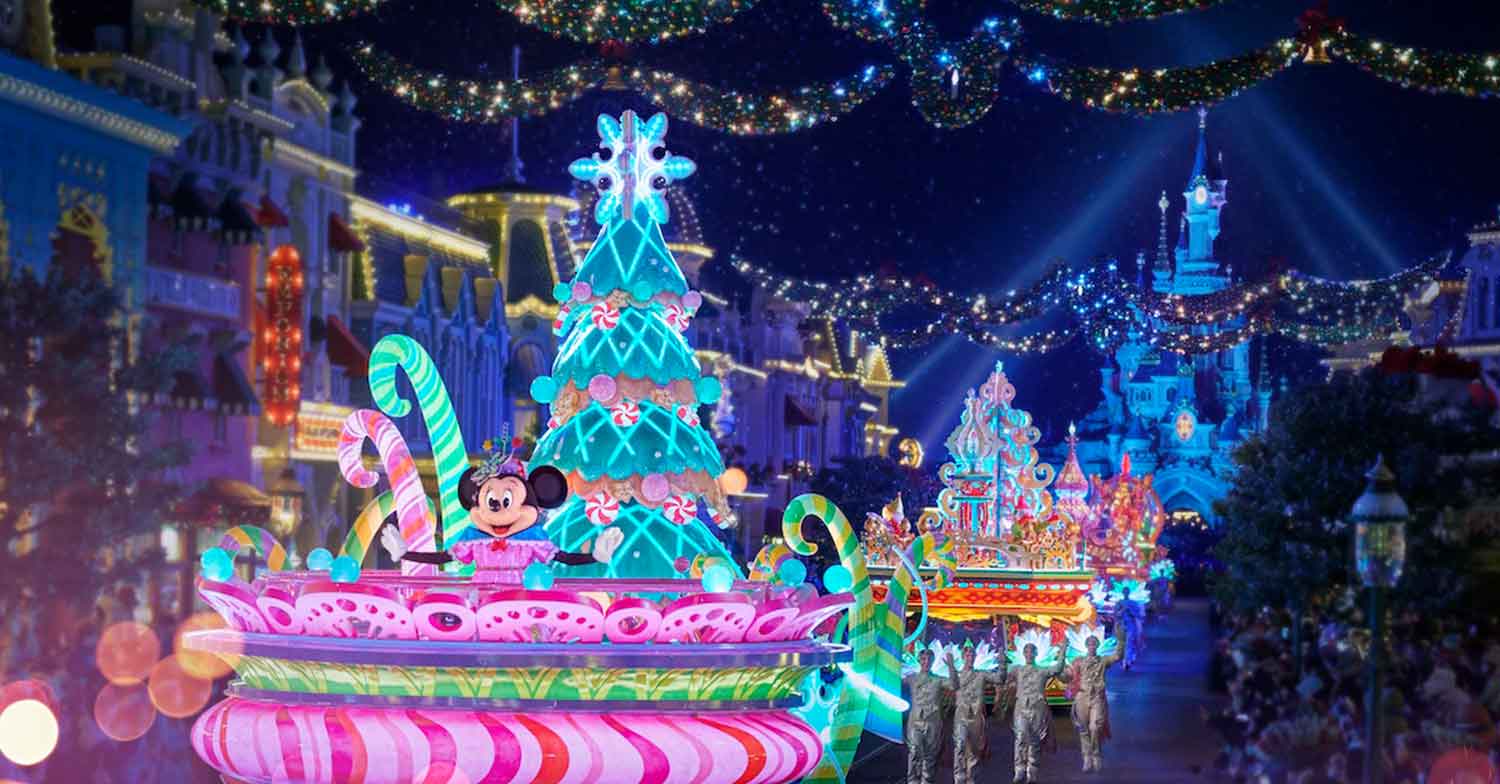 Weihnachten 2023: Mickys Dazzling Christmas Parade mit bunten Wagen und festlich gekleideten Charakteren bei Nacht in Disneyland Paris, 2023