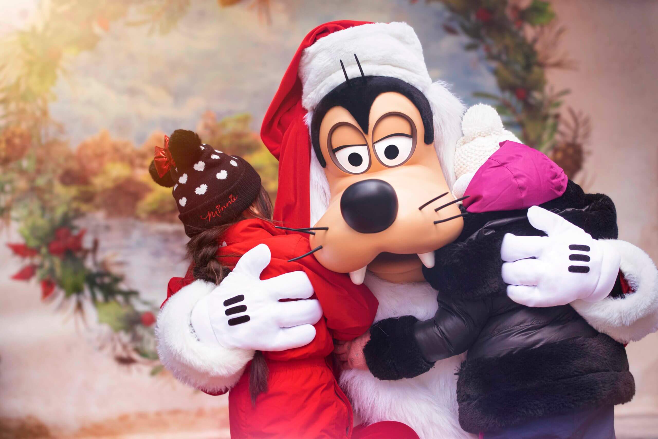 Weihnachtlich gekleideter Goofy umarmt Kinder bei festlicher Begegnung in Disneyland Paris