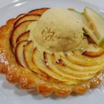 Tarte Tartin mit einer Kugel Vanilleeis, die langsam schmilzt und zwei frischen Apfelspalten