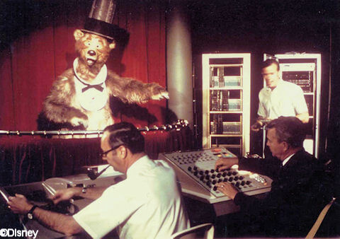 Zwei Disney Imagineers programmieren den Audio Animatronic eines Bären mit Zylinder und Fliege