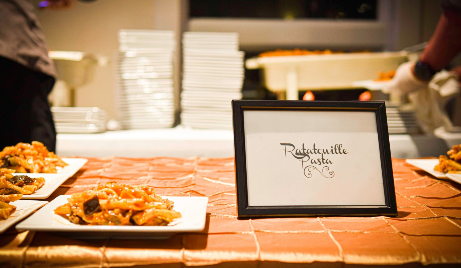 Teller mit Pasta und Ratatouille sowie eine Tafel, auf der auf dieses Gericht hingewiesen wird