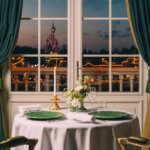 Gedeckter Tisch mit Stühlen vor einem Fenster, das Ausblick auf den Disneyland Park mit dem Sleeping beauty Castle bietet.